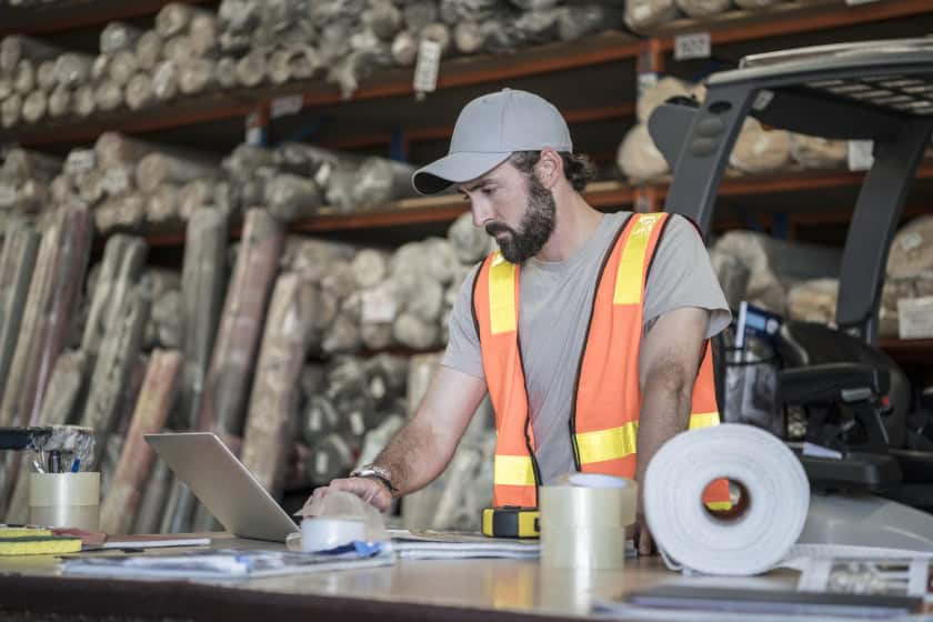Man using laptop in carpet warehouse