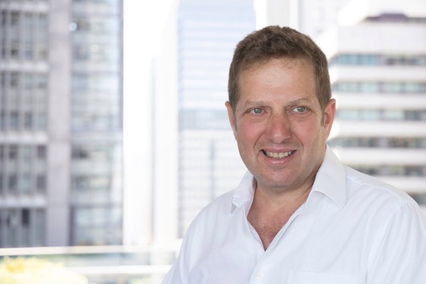 Solomon Forman smiling, he is standing outside and the background is blurred.