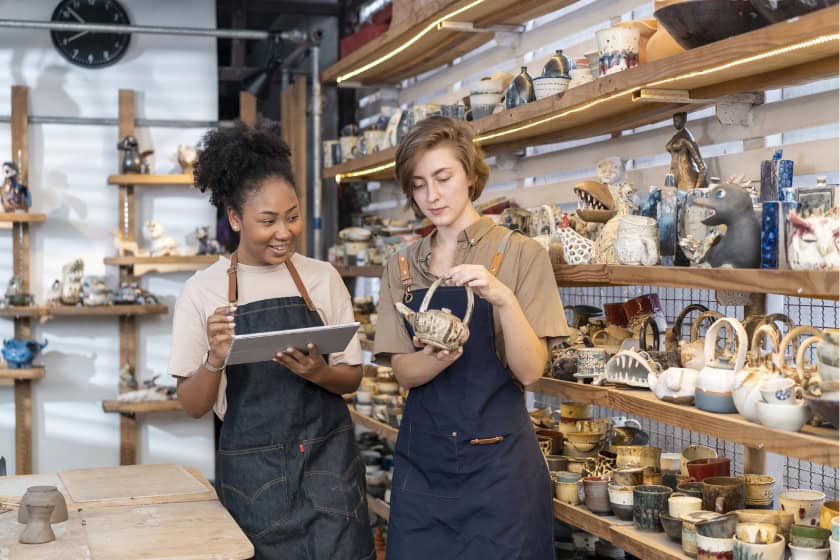 female entrepreneurs discussing over tablet at store