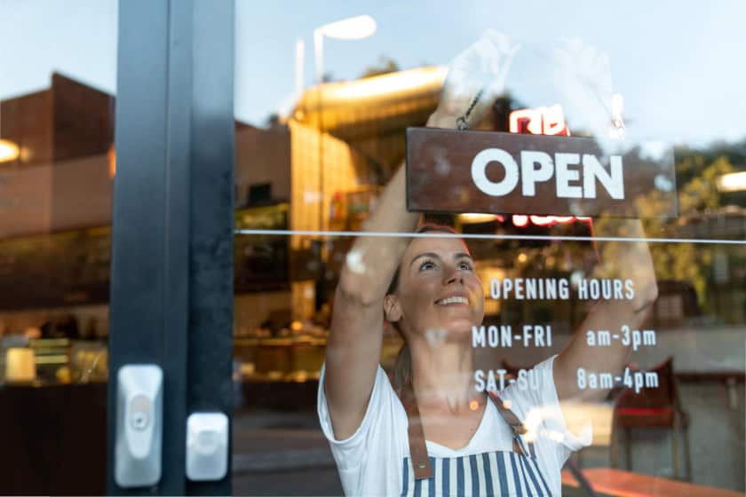 business owner hanging up an open sign at cafe