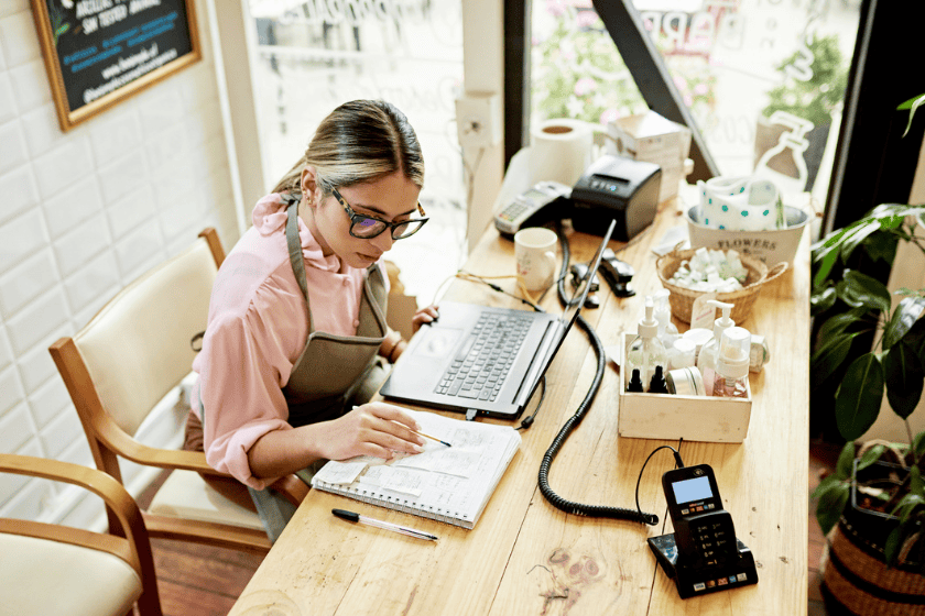Woman in a shop reviewing invoices with a laptop in front of her