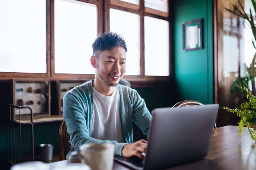 Young asian man working from home, using laptop computer in home office