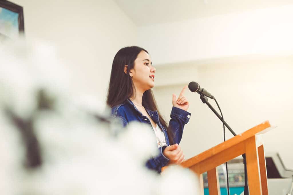 A young woman gives a speech at a podium